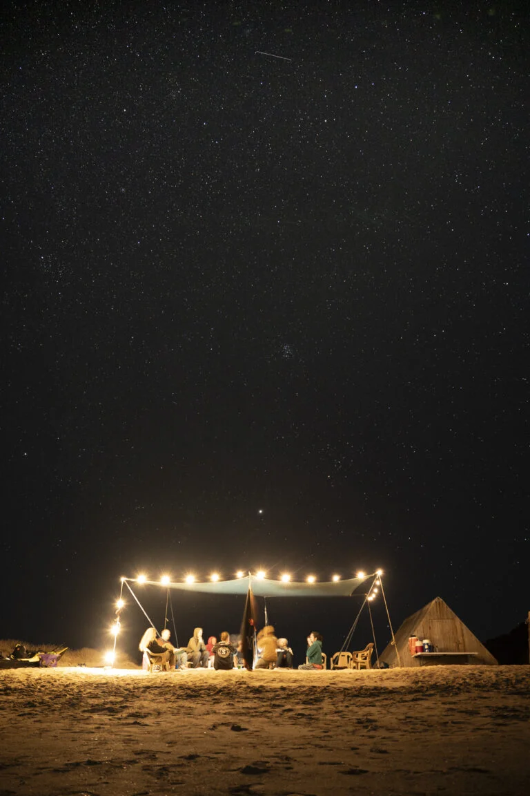 imagen de campamento en Isla Espíritu Santo con personas reunidas alrededor de una fogata bajo un cielo lleno de estrellas