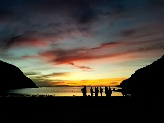 Grupo de personas reunidas en la playa disfrutando del ocaso frente al mar, una de las cosas que hacer en Loreto México.