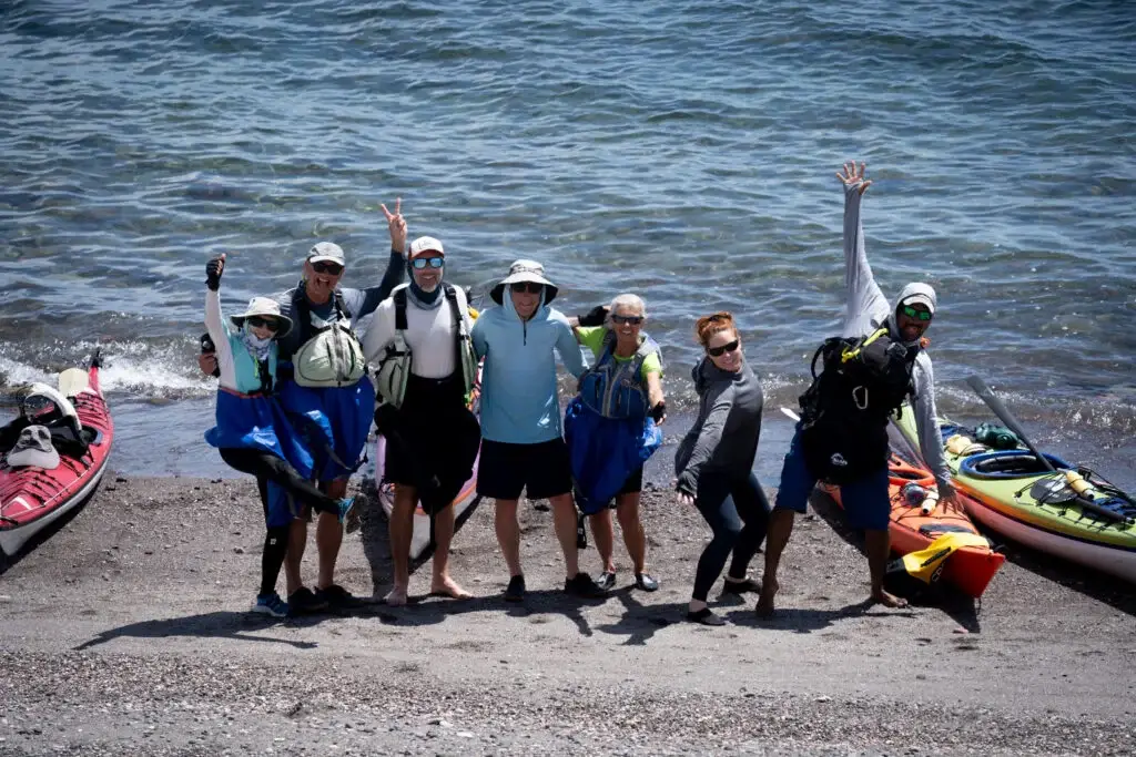 Private trips Seven adventurers wearing sun protection and gear celebrating their arrival or departure from a secluded beach