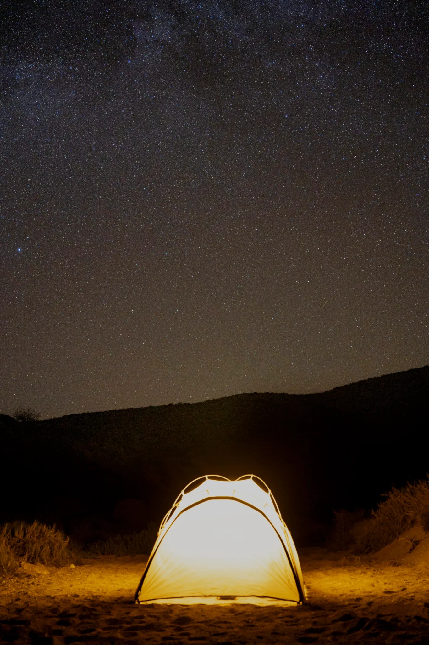 Campamento nocturno con una tienda de campaña resplandeciente bajo un impresionante cielo estrellado, parte de una expedición en el Archipiélago San José